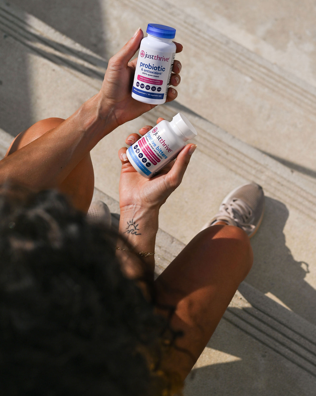 Two hands holding Just Thrive Probiotic and Just Thrive Digestive Bitters