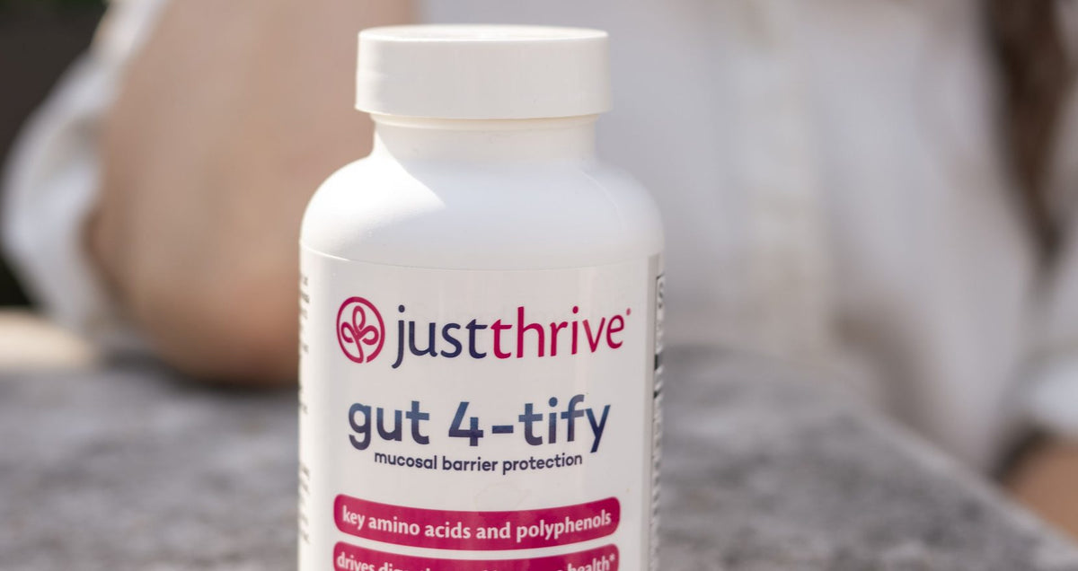 A bottle of Just Thrive Gut 4-tify on a stone surface