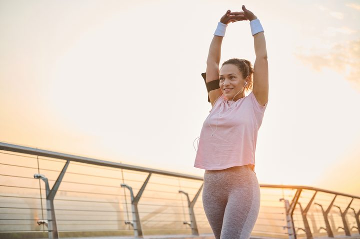 A woman stretching outdoors at sunrise