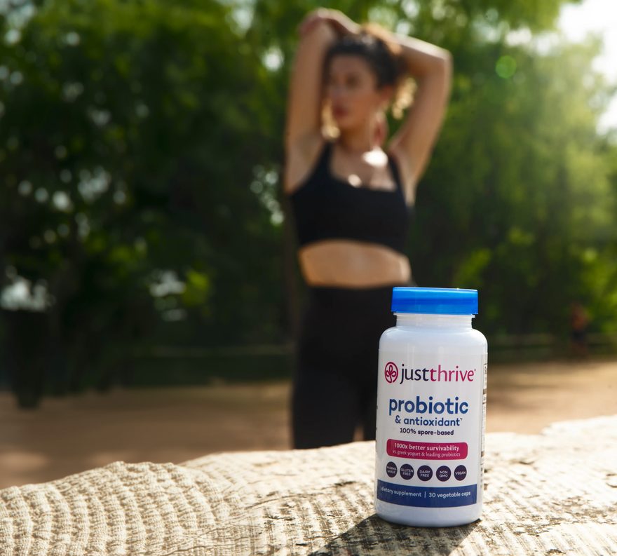 A woman outdoors in a park with Just Thrive Probiotic
