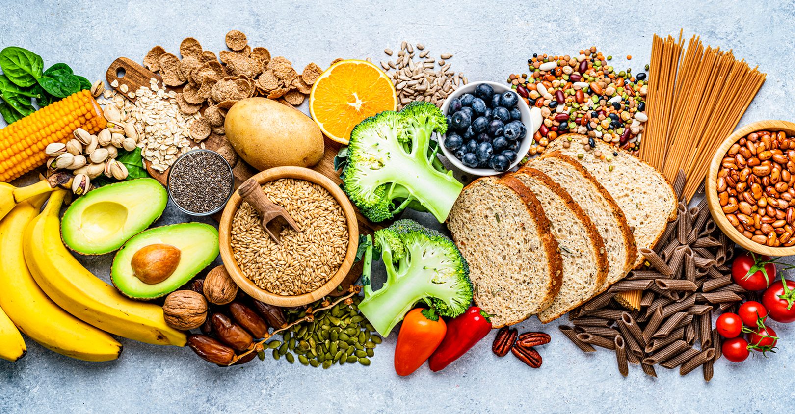 An assortment of high-fiber foods laid out on a grey surface