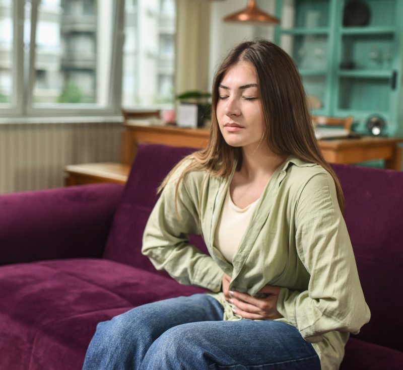 Woman sitting on a sofa with her hands resting on her stomach