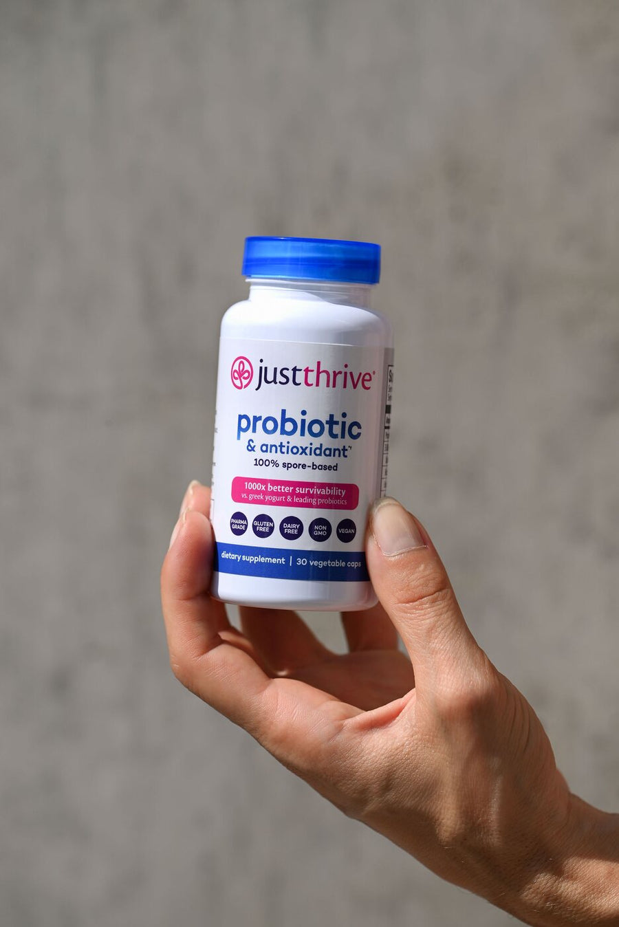 Hand holding a bottle of Just Thrive Probiotic
